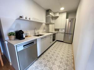 cocina con armarios blancos y nevera de acero inoxidable en Apartamento en el centro de Benasque, en Benasque