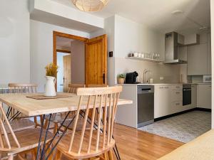 a kitchen and dining room with a wooden table and chairs at Apartamento en el centro de Benasque con piscina in Benasque