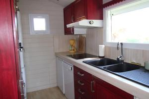 a kitchen with red cabinets and a sink and a window at GASMED29 - Golfe de St-Tropez - Chalet californien dans domaine privé in Gassin