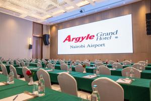 a conference room with green tables and chairs and a large screen at Argyle Grand Hotel Nairobi Airport in Nairobi