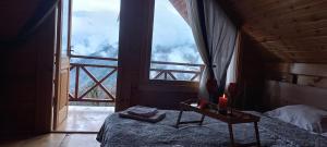 una camera da letto con un letto e una grande finestra di House in the clouds&სახლი ღრუბლებში a Kʼveda Chʼkhutunetʼi