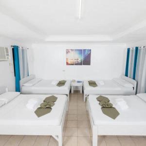 a row of white beds in a room at San Remigio Beach Club in San Remigio