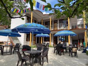 grupa stołów i krzeseł z niebieskimi parasolami w obiekcie Freedom Cafe w mieście Kalgha