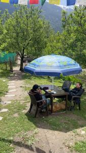trzy osoby siedzące przy stole pod parasolką w obiekcie Freedom Cafe w mieście Kalgha