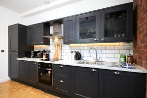 una cocina con armarios negros y fregadero en Sleek New York style Apartment in Central Leeds, en Leeds