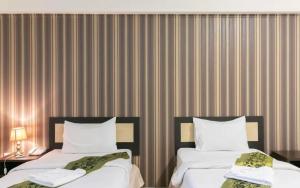 ein Hotelzimmer mit 2 Betten und einer gestreiften Wand in der Unterkunft B9 Airport Resident in Lat Krabang