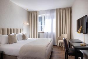 a hotel room with a large white bed and a desk at Best Western Plus Hôtel Isidore in Saint-Jacques-de-la-Lande +87 photos