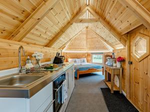 cocina y dormitorio en una cabaña de madera con cama en 1 Bed in Biggar 91250, en Libberton