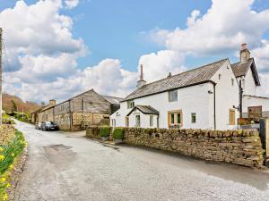 a white house with a stone wall next to a street at 2 Bed in Skipton 91296 in Bolton Bridge