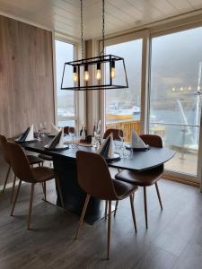 una sala da pranzo con tavolo, sedie e lampadario pendente di Spektakulær rorbu i autentiske omgivelser a Ballstad