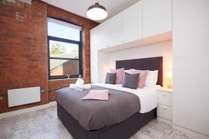 um quarto com uma cama grande e uma parede de tijolos em Sleek New York style Apartment in Central Leeds em Leeds