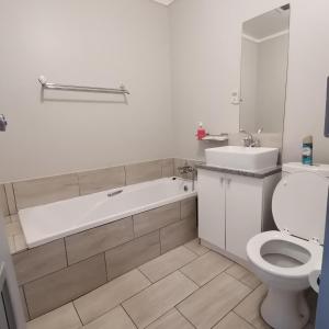 a bathroom with a tub and a toilet and a sink at Indaba Hotel - Sasolburg in Sasolburg