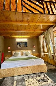 a bedroom with a large bed in a wooden ceiling at Sainj Riverside Cottages in Sainj