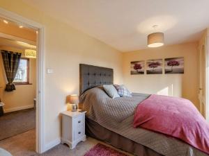 a bedroom with a bed with a pink comforter at 1 Bed in Whitegate 91266 in Whitegate