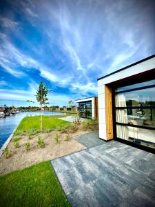 une maison avec une grande porte en verre à côté d'une rivière dans l'établissement MarinaPark Residentie Nieuw Loosdrecht, à Loosdrecht