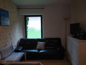 a living room with a black leather couch and a window at Tante Pim in Neuilly-sur-Eure