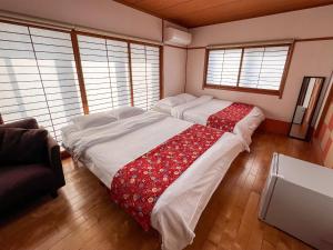 1 Schlafzimmer mit 2 Betten in einem Zimmer mit Fenstern in der Unterkunft Hondori Inn in Hiroshima
