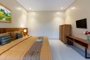 ein Schlafzimmer mit einem großen Bett und einem TV an der Wand in der Unterkunft Rahayu Hanoman Ubud in Ubud