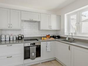 uma cozinha branca com armários brancos e um lavatório em 1 Bed in Barnstaple 91612 em Bishops Tawton