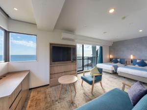 a hotel room with two beds and a television at Atagawa Ocean Resort in Higashiizu