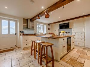 uma cozinha com armários brancos e um balcão com bancos em 5 Bed in Keswick 91503 em Embleton