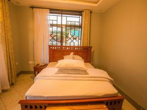 Bett in einem Zimmer mit Fenster in der Unterkunft Medan Hotel in Ngateu