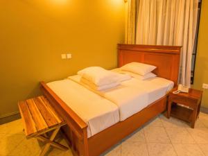 Schlafzimmer mit einem Bett mit einem Kopfteil aus Holz und einem Tisch in der Unterkunft Medan Hotel in Ngateu