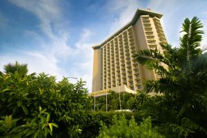 ein hohes Gebäude mit Bäumen davor in der Unterkunft Century Park Hotel in Manila