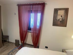 a bedroom with a bed and a window with red curtains at Archetto-casa vacanze in Enna