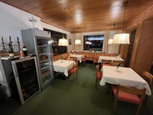 un restaurante con mesas, sillas y nevera en Pension Alpina, en Obsteig