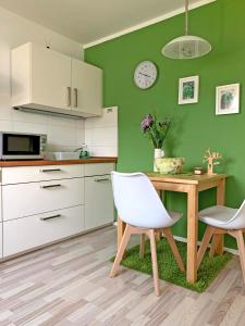 eine Küche mit einem Tisch und 2 weißen Stühlen in der Unterkunft Ferienwohnung Zimmergrün am Nordpark in Mönchengladbach