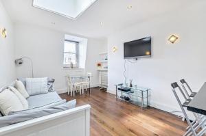 ein Wohnzimmer mit einem Sofa und einem TV an der Wand in der Unterkunft Chancery's Loft Private Apartment in London