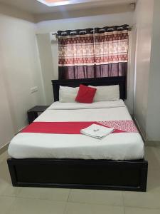 a bed with a red pillow and a book on it at HOTEL MOUNTAIN PARADISE in Bangalore