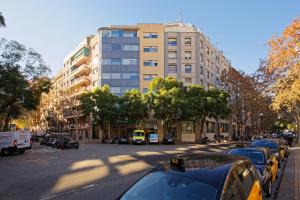 una strada di città con auto parcheggiate di fronte a un edificio alto di Green House Hotel a Barcellona