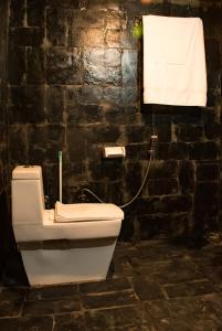 a white toilet in a bathroom with a brick wall at Sainj Riverside Cottages in Sainj