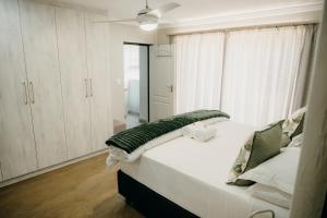 a bedroom with a large white bed with white cabinets at Ruzelle Family House in Hazyview