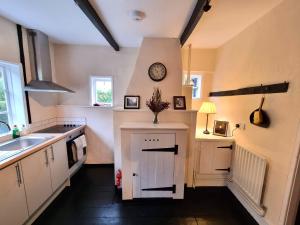uma cozinha com um lavatório e um relógio na parede em Gardener's Cottage, Knebworth Park em Knebworth