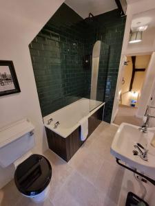 uma casa de banho com uma banheira, um WC e um lavatório. em Gardener's Cottage, Knebworth Park em Knebworth