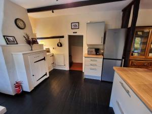 a kitchen with white cabinets and a refrigerator at Gardener's Cottage, Knebworth Park in Knebworth