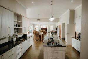 a large kitchen with white cabinets and a living room at Ruzelle Family House in Hazyview
