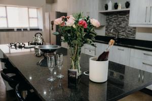 a bottle of wine and a vase of flowers on a kitchen counter at Ruzelle Family House in Hazyview