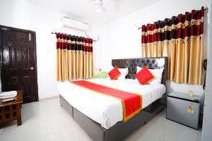 a bedroom with a bed with red and yellow curtains at Hotel Brundavan Homes in Hyderabad +46 photos