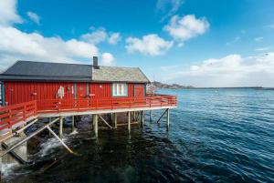 ein rotes Haus auf einem Dock im Wasser in der Unterkunft Explorers Cabin Lofoten Edge in Sørvågen