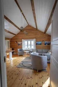ein Wohnzimmer mit einem Sofa und Stühlen in einem Zimmer in der Unterkunft Explorers Cabin Lofoten Edge in Sørvågen