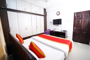 - une chambre avec un lit doté d'oreillers rouges et jaunes dans l'établissement Hotel Brundavan Homes, à Hyderabad