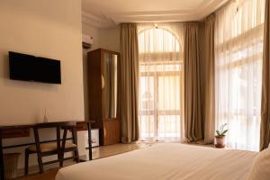a hotel room with a bed and a large window at Tamarin Hôtel in Cotonou