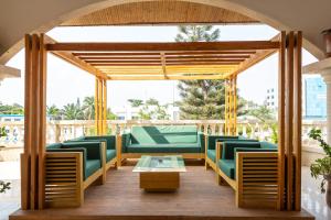 a pavilion with green chairs and a table at Tamarin Hôtel in Cotonou