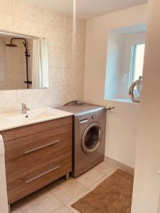 Un baño con lavadora y lavabo. en Maison de campagne, en Saint-Santin-Cantalès