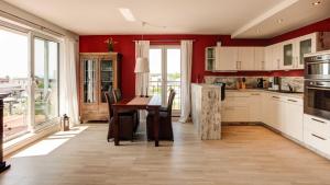 cocina con paredes rojas y mesa de madera con escritorio en Villa am Kreidebruch _ Komfort_App, en Sassnitz