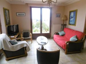 ein Wohnzimmer mit einem roten Sofa und Stühlen in der Unterkunft Maison 4 pièces 6 personnes, vue sur l'océan - Carantec in Sarzeau